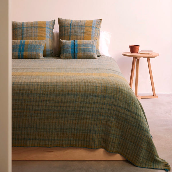 blankets and matching pillow covers in rectangular and square shapes in 100% Merino wool. Llghtweight, flat woven pieces made with 100% pure Merino wool woven in 5 shades of olive green & turquoise colors
