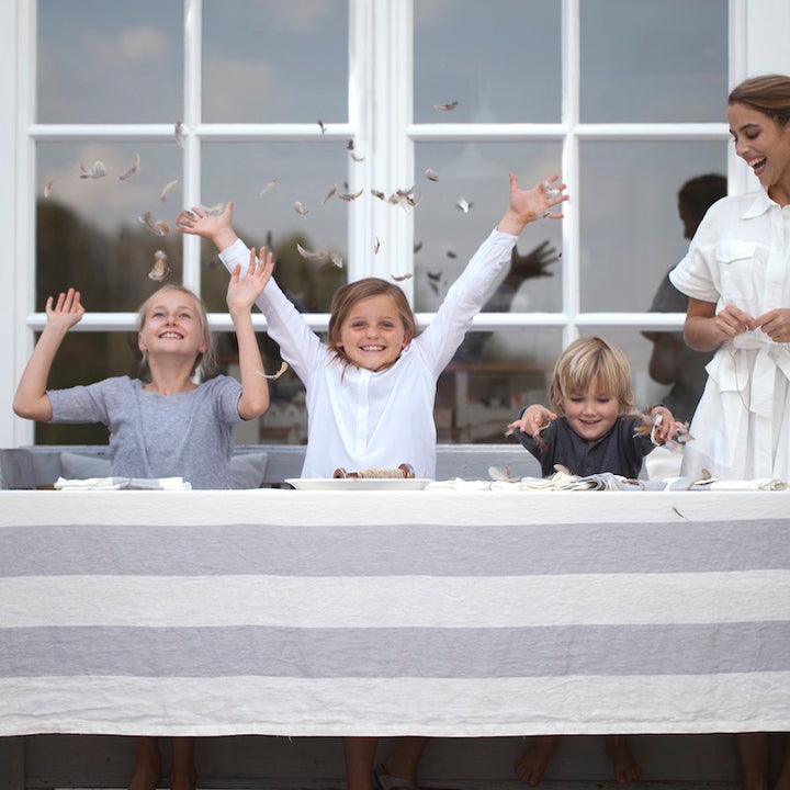 A family celebrating a birthday party on a long 10-foot-table on an outdoor setting with Libeco Belgian linen tablecloth, Long Islandn