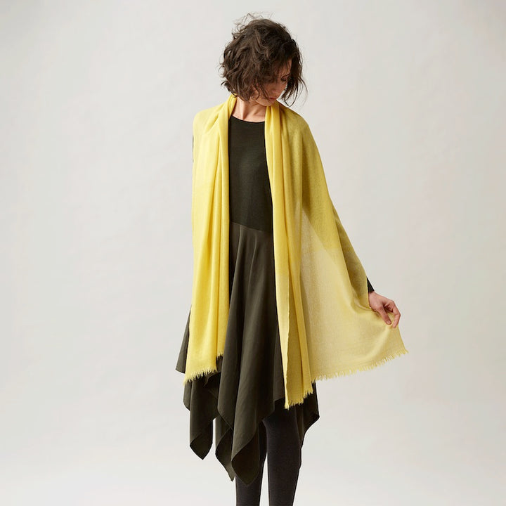 Mustard yellow shawl, woven by hand loom in Terrassa (Barcelona), using the supreme delicacy of cashmere fibre, design by Helena Rohner for Teixidors is the finest Italian cashmere  worn by a woman wearing it casually elegant 