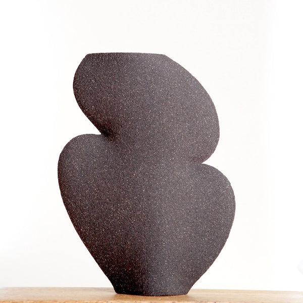 abstract curvy shaped black vase is handmade in Paris with chamotte texture on the exterior and smooth glaze inside